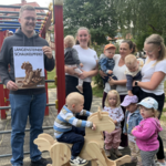 Kinder und Erwachsene freuen sich sehr über den Beginn der Kooperation mit der Tischlerei Bögelsack – symbolisiert durch das geschenkte Schaukelpferd.