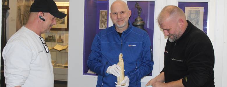 Museologe André Pohl (Mitte) mit der Bischofsfigur zwischen den Fachleuten von DB Schenker
