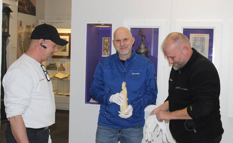 Museologe André Pohl (Mitte) mit der Bischofsfigur zwischen den Fachleuten von DB Schenker